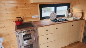 a tiny kitchen with a stove and a sink at Behagliches OFFGRID Tiny House - Escape to Nature in Sankt Pölten