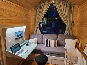 a living room with a couch and a laptop on a desk at Behagliches OFFGRID Tiny House - Escape to Nature in Sankt Pölten