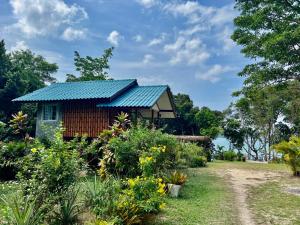 a small house with a blue roof in a garden at Spiral Resort in Ko Phayam