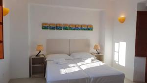 ein Schlafzimmer mit einem weißen Bett mit zwei Tischen und zwei Lampen in der Unterkunft Villa Patmos Netia - Location Xoxlakas in Patmos