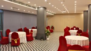 uma sala de conferências com cadeiras vermelhas e mesas brancas em Hibiscus Select Hotel em Noida