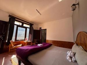 Beholden Stay and Cafe في مانالي: غرفة نوم بسرير كبير مع بطانية ارجوانية