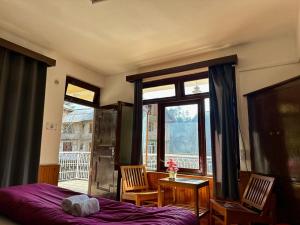 1 dormitorio con cama, mesa y ventana en Beholden Stay and Cafe, en Manali