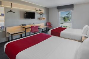 a hotel room with two beds and a desk and a table at City Express by Marriott Durango in Durango