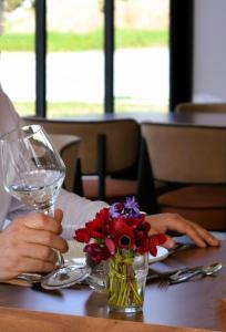 a person sitting at a table with a wine glass and flowers at Pamukkale Kaya Thermal Spa Hotel in Pamukkale
