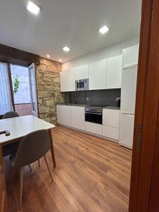 una cocina con armarios blancos y una mesa con sillas. en Kareharri Piso en Casco Viejo de Zarautz en Zarautz