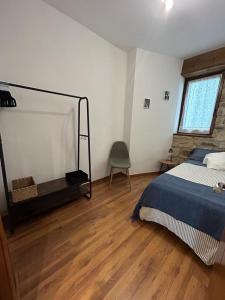 a bedroom with a bed and wooden floors and a window at Kareharri Piso en Casco Viejo de Zarautz in Zarautz