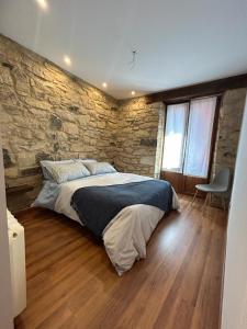 Un dormitorio con una pared de piedra y una cama grande. en Kareharri Piso en Casco Viejo de Zarautz, en Zarautz