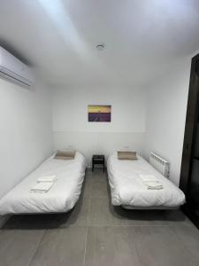Hostal La Masia في مانريسا: سريرين في غرفة بجدران بيضاء