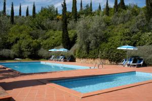 a swimming pool with two chairs and umbrellas at Comiti Farmhouse Apt Bondone in Montaione +8 photos