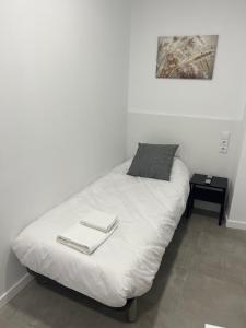 uma cama branca com duas toalhas em cima em Hostal La Masia em Manresa