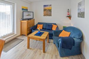 ein Wohnzimmer mit einem blauen Sofa und einem Tisch in der Unterkunft Friesenstübchen in Dornumersiel