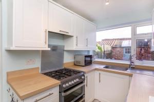 a kitchen with white cabinets and a stove top oven at House in Malton in Norton