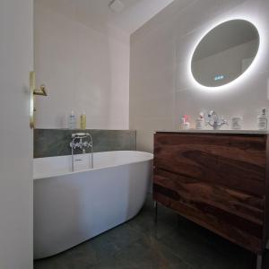 een badkamer met een bad, een wastafel en een spiegel bij Villa Andrena in Talence