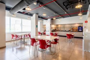 a restaurant with red chairs and tables and a kitchen at City Express Junior by Marriott Tuxtepec in San Juan Bautista Tuxtepec