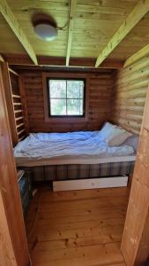 ein kleines Bett in einer Holzhütte mit einem Fenster in der Unterkunft Hirsimökki kansallispuistossa in Espoo