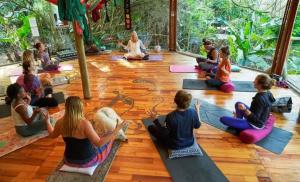um grupo de pessoas sentadas no chão em uma aula de yoga em Mantis and Moon Backpackers and Surf Hostel em Hibberdene