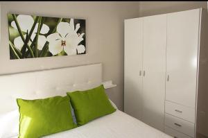 a bedroom with a white bed with green pillows at Ritual Sevilla, piedra preciosa in Seville