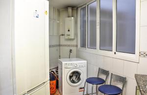 uma cozinha com uma máquina de lavar roupa e 2 bancos azuis em Ritual Sevilla, piedra preciosa em Sevilha
