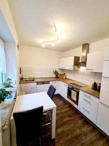 a kitchen with white cabinets and a white table at Schöne Ferienwohnung im Schwarzwald in Bad Herrenalb