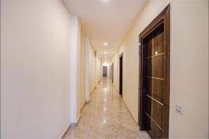 un couloir avec un long couloir aux murs blancs et une porte dans l'établissement FabExpress Red Diamond, à Ghaziabad