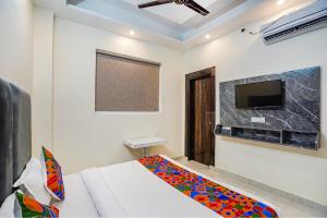 FabExpress Red Diamond في غازي آباد: غرفة نوم مع سرير وتلفزيون على الحائط