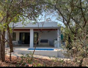 a small white house with a patio and trees at Bushbuck Rest in Marloth Park