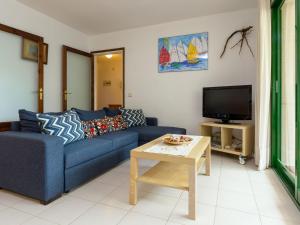 uma sala de estar com um sofá azul e uma televisão em Apartamento Llançà, 2 dormitorios, 5 personas - ES-228-41 em Llançà