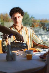 ローダにあるRobolla Beach Aparthotelの食卓に座っている男