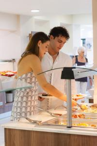 a man and a woman preparing food in a kitchen at Robolla Beach Aparthotel in Roda