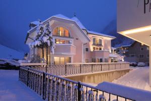 una casa blanca con una cerca en la nieve en Grütter Luxury Apartments, en Ischgl