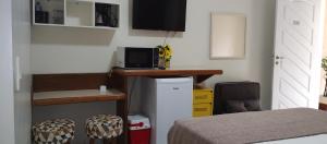 1 dormitorio con 1 cama y escritorio con TV en RIVIERA SERVICE- Suíte Casal -113 en Bertioga