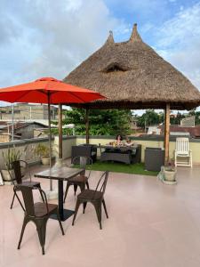een patio met een tafel en stoelen en een rieten parasol bij Résidence Maronne in Porto-Novo