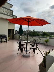 a table and chairs with a red umbrella on a balcony at Résidence Maronne in Porto-Novo