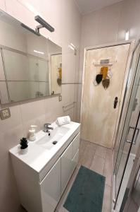 uma casa de banho com um lavatório e um chuveiro com um espelho. em Wave Beach House em Vila do Conde