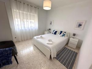 a white bedroom with a large bed and a chair at Wave Beach House in Vila do Conde