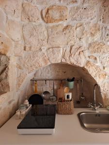 uma cozinha com uma parede de pedra e um lavatório em Residenza Anima Mediterranea em Francavilla Fontana