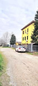 un coche aparcado al lado de una carretera junto a un edificio amarillo en Verdi Valli Comfort B&B Mirandola, 