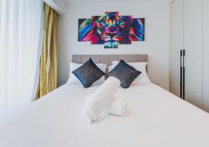 a bedroom with a white bed with a lion painting on the wall at Rosewood luxury 1 bedroom @ Solaris in Accra