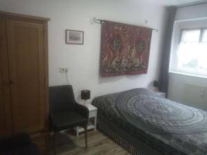 1 dormitorio con 1 cama, 1 silla y 1 ventana en ELBENLAND SÄCHSISCHE SCHWEIZ II - Komfortable 2-Raum-Wohnung im Herzen der sächsischen Schweiz, en Sebnitz