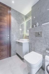 a white bathroom with a toilet and a sink at Rosewood luxury 1 bedroom @ Solaris in Accra