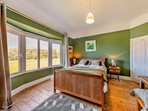 a bedroom with green walls and a bed and windows at 4 Bed in Fairbourne 42772 in Fairbourne