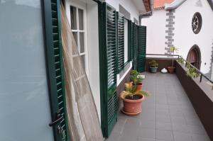 a balcony with green shutters and potted plants at Casas do Largo Dos Milagres in Machico