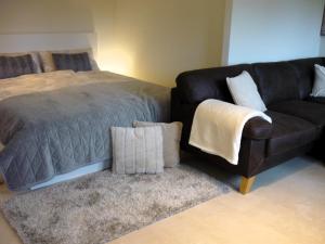 ein Schlafzimmer mit einem Bett und einem Sofa neben einem Bett in der Unterkunft Bungalow Oase der Ruhe in Lobbe + 9 Fotos