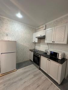 La cuisine est équipée de placards blancs et d'un réfrigérateur blanc. dans l'établissement ЖК Ashyq Tobe, à Almaty