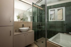 a bathroom with a sink and a glass shower at Touching Acropolis - Quiet & Elegant 1-Bdr Apt in Athens