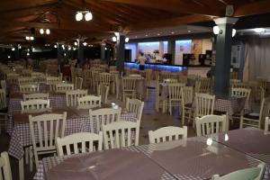 ein Zimmer mit Tischen und weißen Stühlen in der Unterkunft Angela Beach Hotel & Apts in Roda