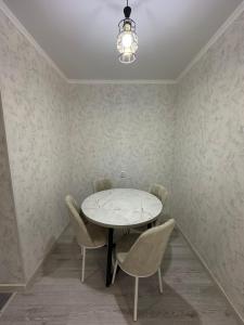 une salle à manger avec une table et des chaises blanches dans l'établissement ЖК Ashyq Tobe, à Almaty