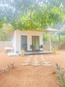 una piccola casa bianca con due sedie davanti di Ima Villa Sigiriya a Sigiriya