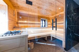 a sauna with wooden walls and a glass wall at Der Schlosswirt zu Anif - Biedermeierhotel und Restaurant in Anif